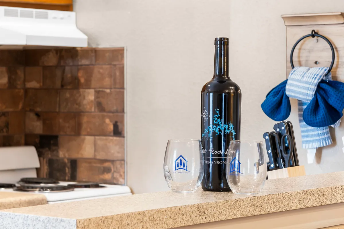 A warmly lit interior featuring a wine bottle and glasses on a kitchen counter, hinting at intimate dinners and celebratory toasts. The inviting setup suggests a private, romantic meal prepared and enjoyed in comfort.